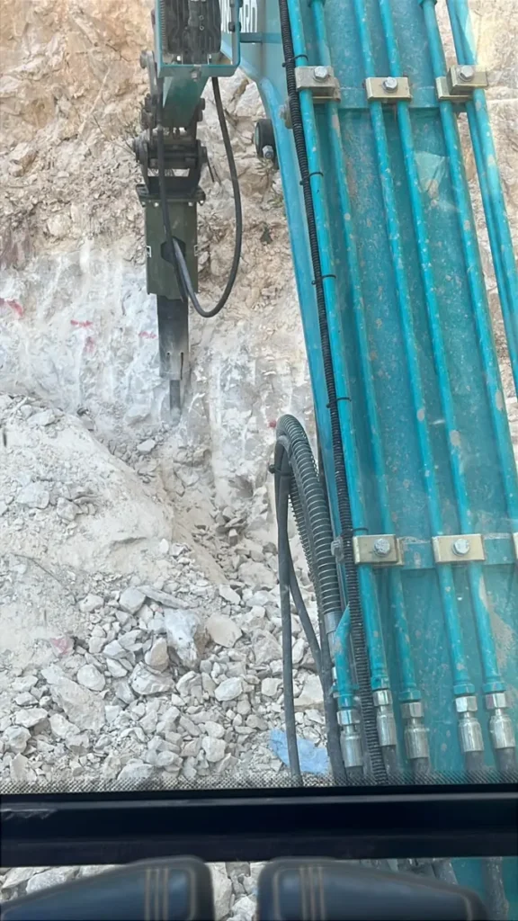 פטיש הידראולי על באגר חוצב בקיר סלע גיר לבן, מבט מתוך תא המפעיל