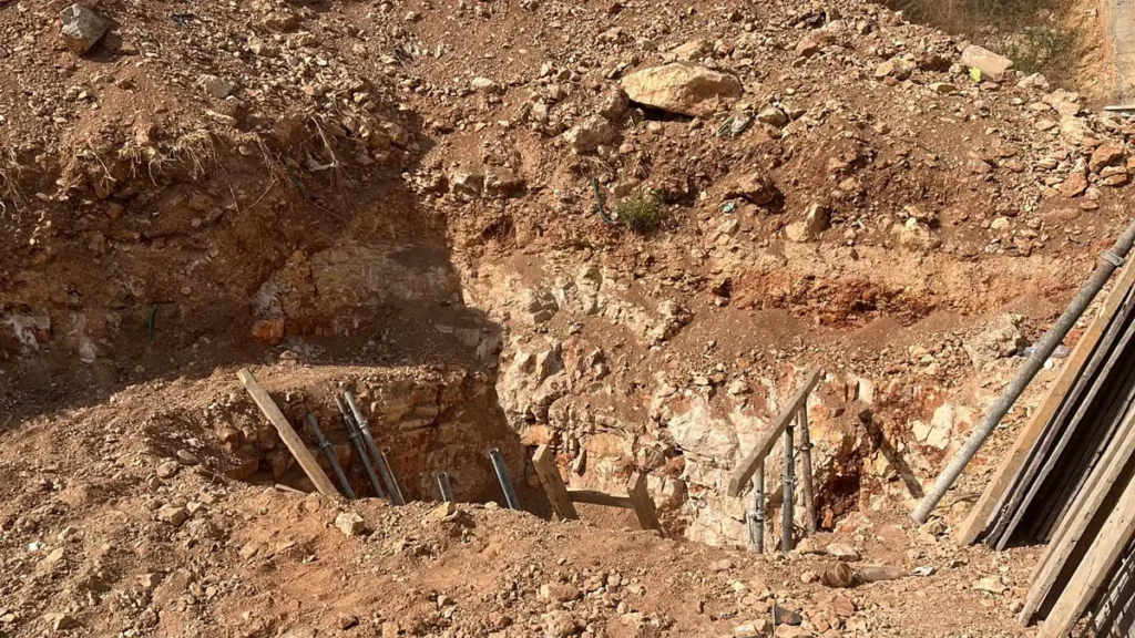 בור חפירה ליסודות בקרקע סלעית: שכבות סלע גיר ואדמה אדומה, עם סמכים ולוחות עץ