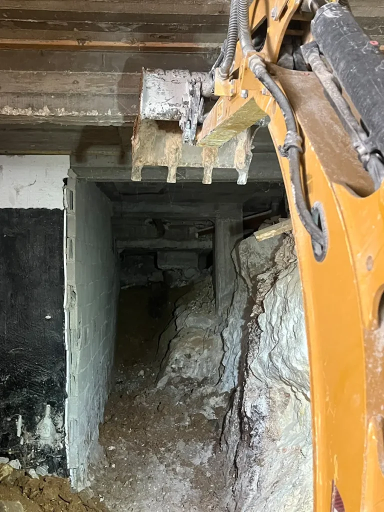 כף מיני מחפרון מתחת לתקרת בטון, חפירת מרתף בסלע מתחת לבית קיים